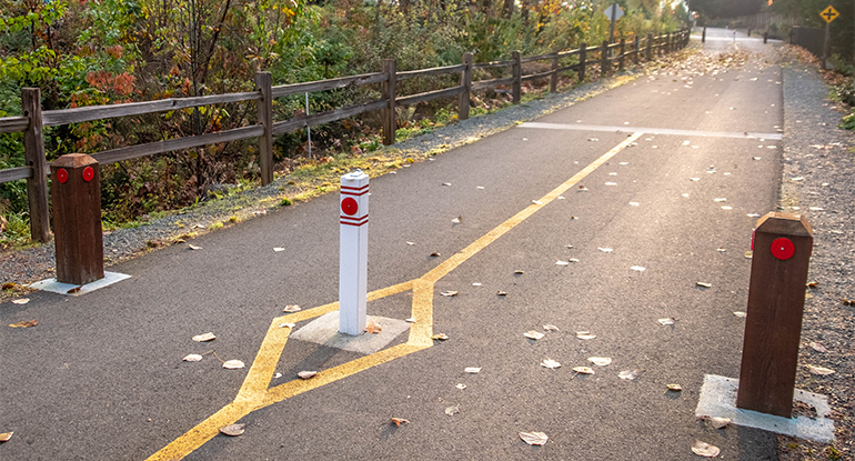 Photo shows single bollard on a paved pedstrian road.